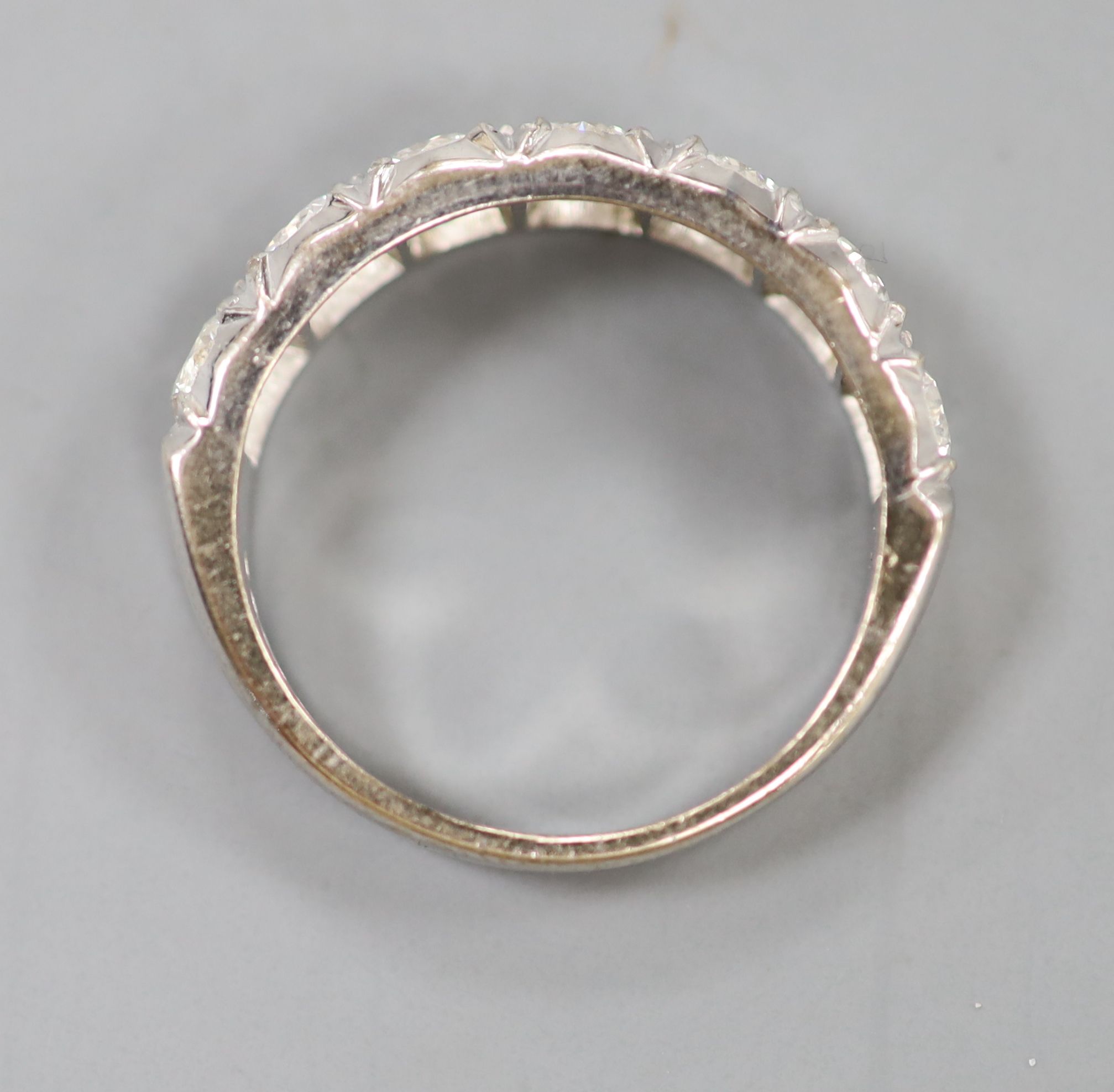 A modern 18ct white gold and seven stone diamond set half hoop ring